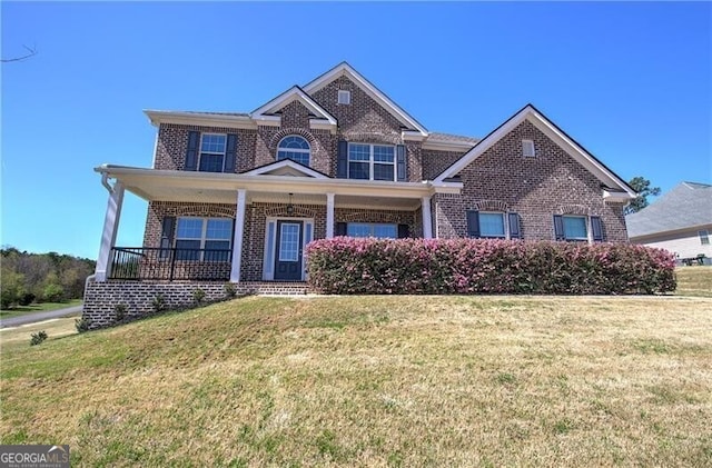 craftsman-style house featuring covered porch, brick siding, and a front yard