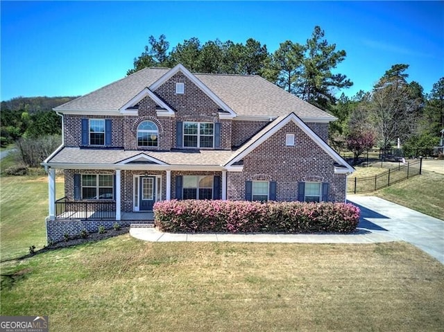 craftsman-style house with brick siding, fence, a porch, and a front yard