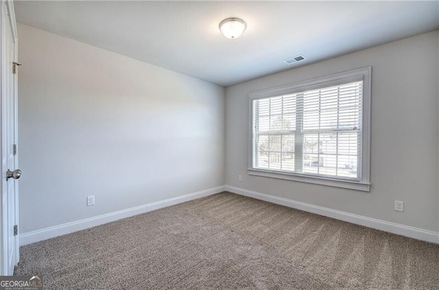 carpeted spare room with visible vents and baseboards
