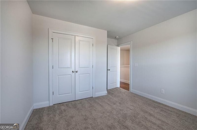 unfurnished bedroom with carpet floors, a closet, and baseboards