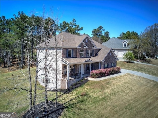 view of front facade featuring a front lawn, brick siding, driveway, and covered porch