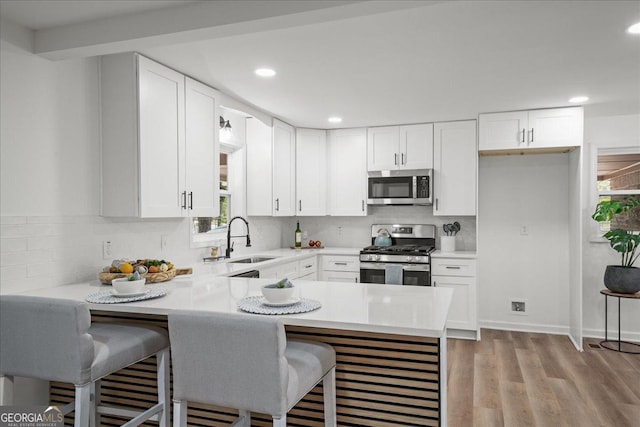 3951 Covered Bridge Rd SW, Smyrna, GA 30082 - kitchen with appliances with stainless steel finishes, a sink, light countertops, a peninsula, and white cabinetry