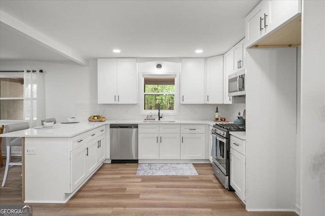 3951 Covered Bridge Rd SW, Smyrna, GA 30082 - kitchen with appliances with stainless steel finishes, a peninsula, a sink, white cabinets, and recessed lighting