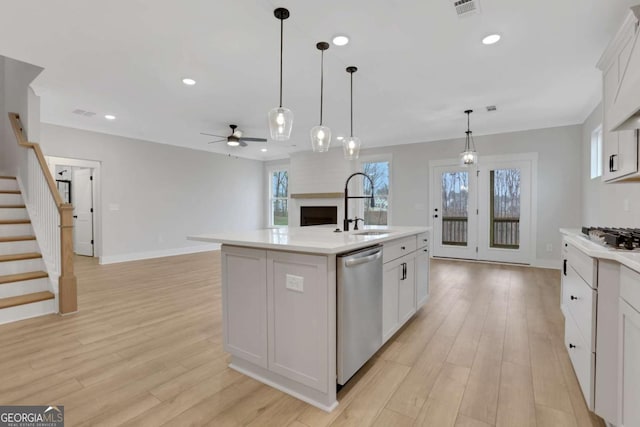 kitchen with stainless steel dishwasher, light countertops, ceiling fan, and a sink
