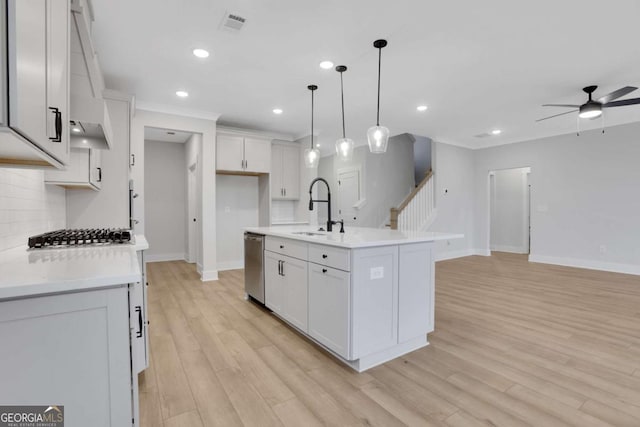 kitchen featuring light countertops, decorative backsplash, a sink, ceiling fan, and appliances with stainless steel finishes