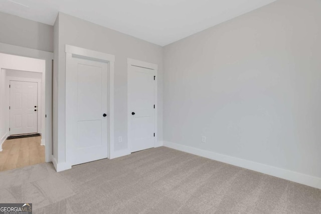 unfurnished bedroom with baseboards and light colored carpet