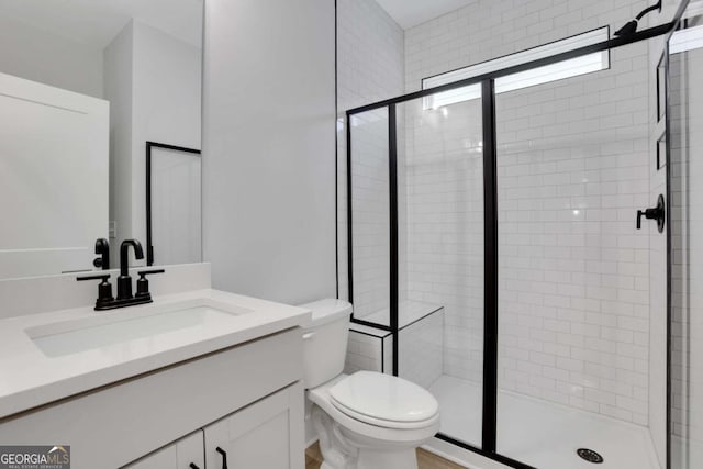 bathroom featuring toilet, vanity, and a stall shower