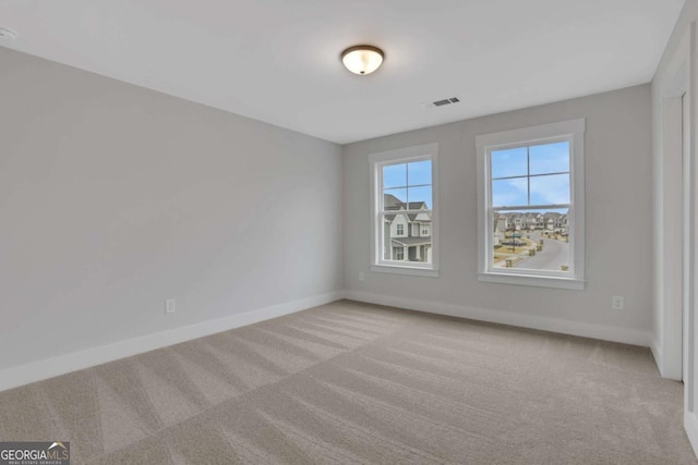 spare room featuring carpet flooring, baseboards, and visible vents