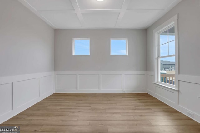 spare room featuring light wood finished floors, wainscoting, and coffered ceiling