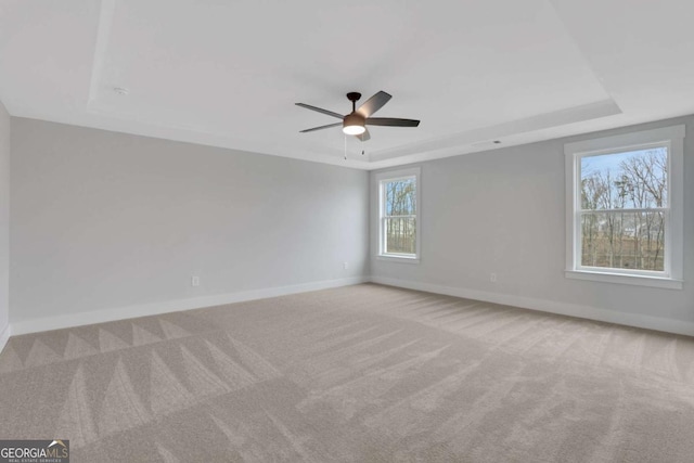 carpeted spare room featuring baseboards, a ceiling fan, and a raised ceiling