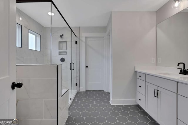 full bath featuring vanity, a stall shower, and baseboards
