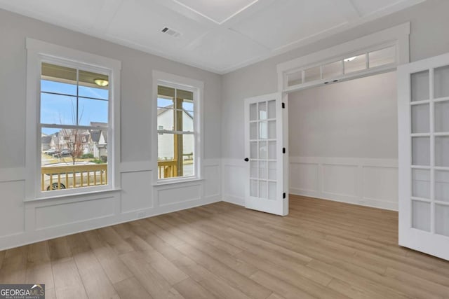 spare room with a decorative wall, visible vents, french doors, and light wood finished floors