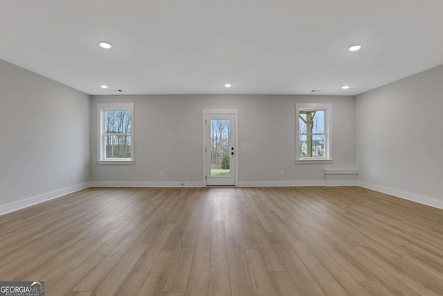 unfurnished living room featuring baseboards, a wealth of natural light, and light wood-type flooring