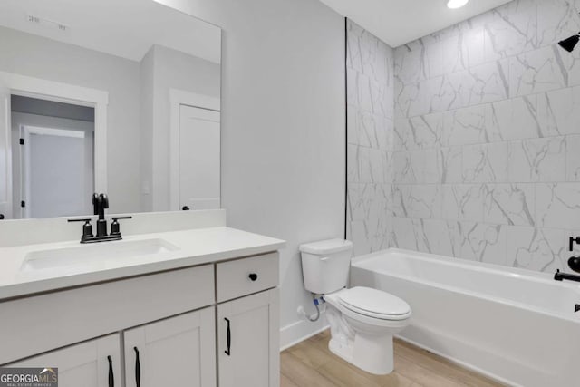 full bathroom with toilet, vanity, wood finished floors, washtub / shower combination, and visible vents