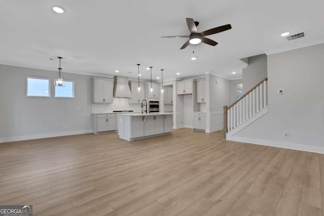 kitchen with premium range hood, open floor plan, light wood-type flooring, visible vents, and ceiling fan