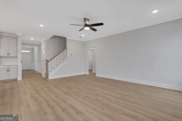 unfurnished living room featuring stairs, a ceiling fan, light wood finished floors, baseboards, and recessed lighting