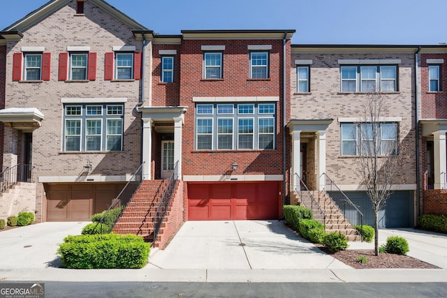 multi unit property with brick siding, driveway, stairway, and an attached garage