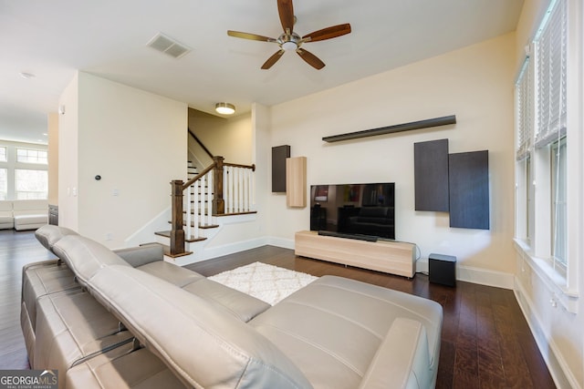 living room with stairway, dark wood-type flooring, baseboards, ceiling fan, and visible vents