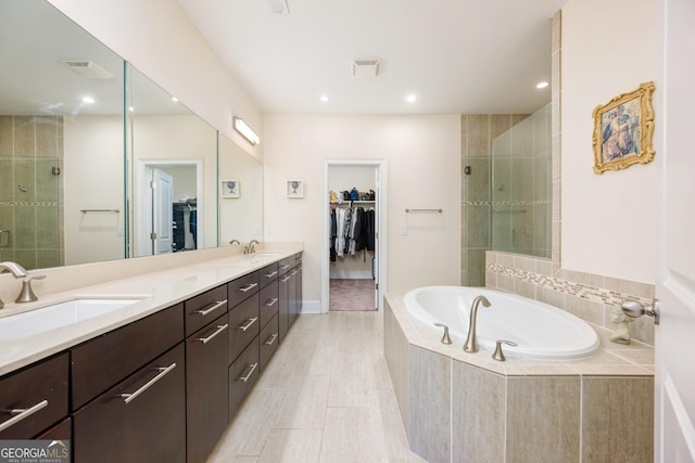bathroom featuring a stall shower, a bath, a walk in closet, and a sink