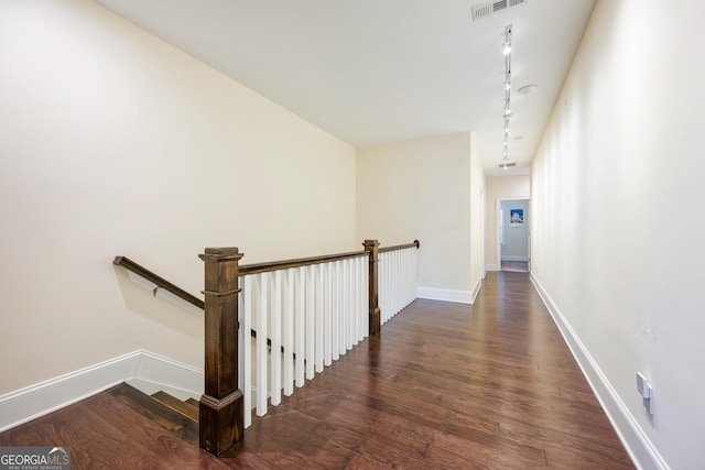 hall featuring an upstairs landing, visible vents, track lighting, baseboards, and wood finished floors