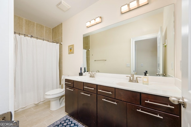 bathroom with toilet, a sink, double vanity, and visible vents