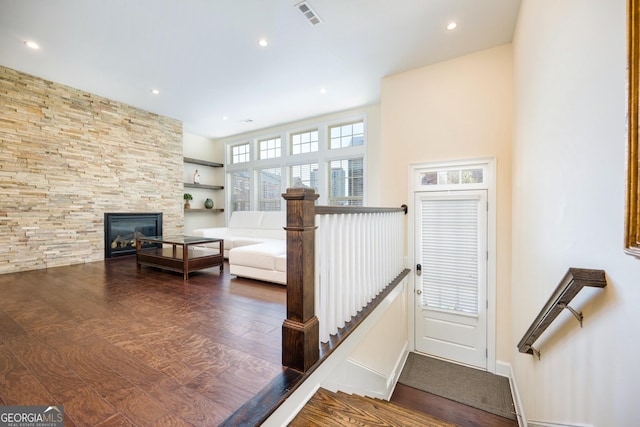 stairs featuring a fireplace, wood finished floors, baseboards, visible vents, and recessed lighting