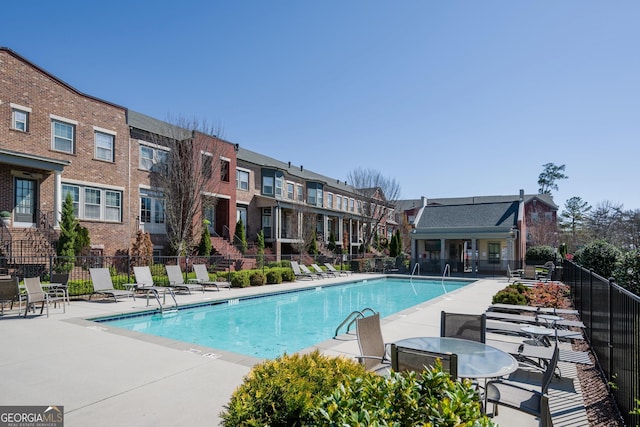 community pool with a residential view, fence, and a patio