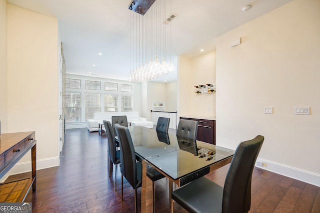 dining area with dark wood-type flooring, visible vents, baseboards, and a chandelier