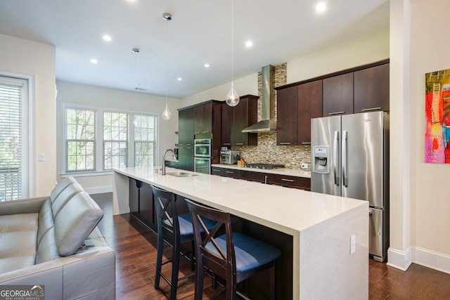 kitchen featuring a sink, wall chimney exhaust hood, tasteful backsplash, appliances with stainless steel finishes, and dark wood-style floors