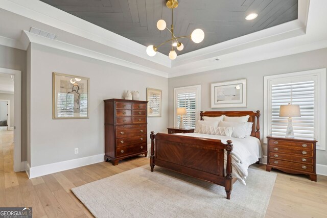 bedroom with an inviting chandelier, a raised ceiling, light wood finished floors, and baseboards