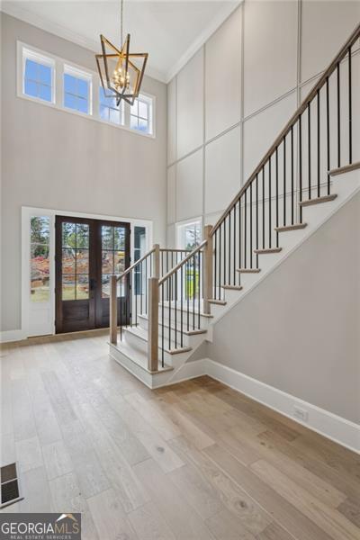 foyer featuring baseboards, a chandelier, wood finished floors, and stairway
