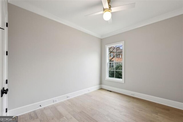empty room featuring crown molding, baseboards, ceiling fan, and light wood-style flooring
