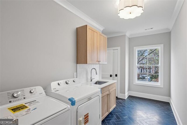 laundry area featuring crown molding, baseboards, separate washer and dryer, a sink, and cabinet space