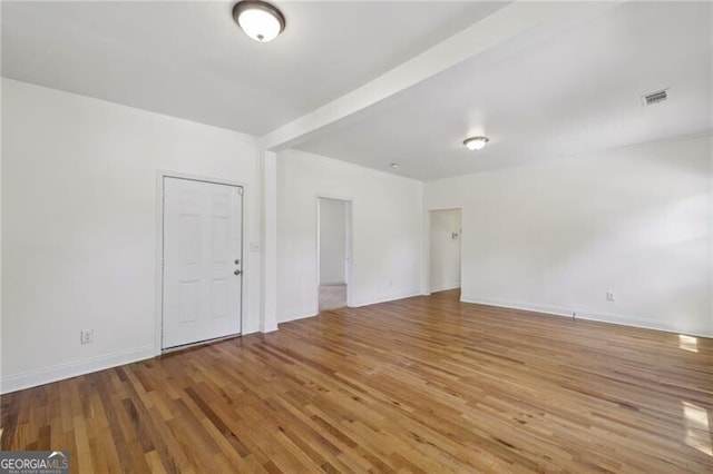 empty room with visible vents, baseboards, and wood finished floors