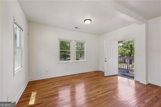 unfurnished room with baseboards, wood finished floors, and visible vents
