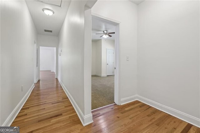 corridor featuring visible vents, light wood finished floors, and baseboards