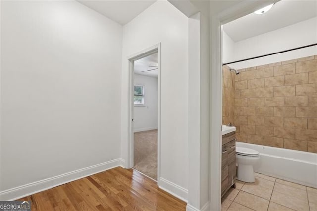 full bathroom with wood finished floors, vanity, shower / washtub combination, baseboards, and toilet