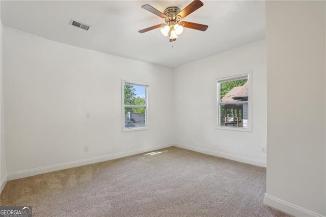 spare room featuring carpet floors, a ceiling fan, visible vents, and baseboards