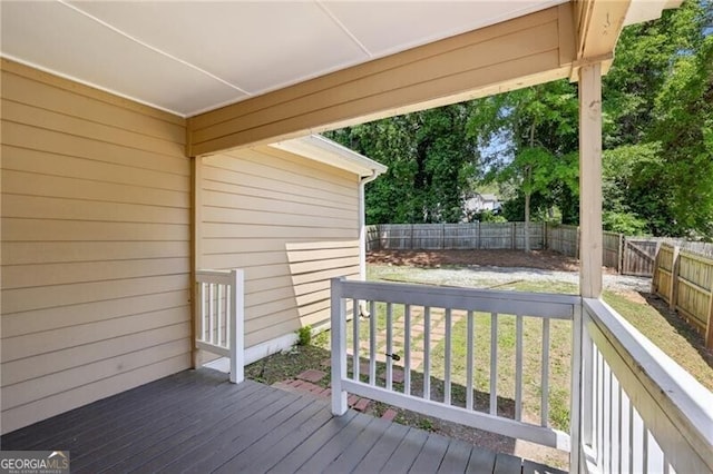 wooden terrace featuring a fenced backyard and a yard
