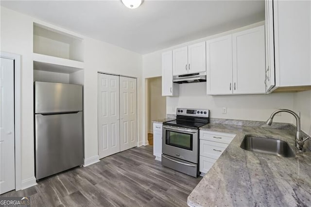 kitchen with a sink, stainless steel appliances, white cabinets, under cabinet range hood, and light stone countertops