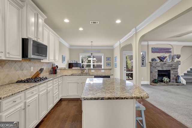 kitchen featuring ornamental molding, stainless steel appliances, a sink, visible vents, and a peninsula