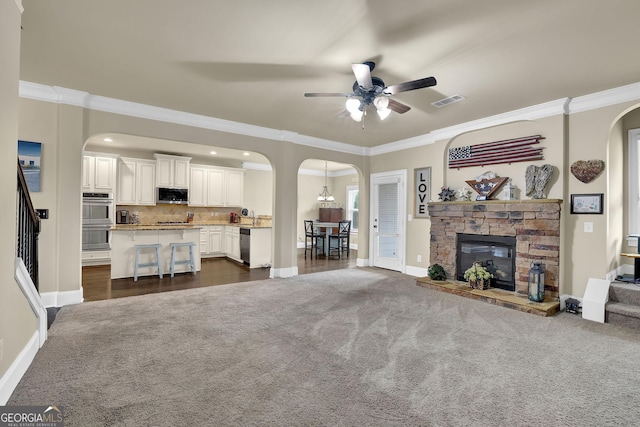living area with arched walkways, dark carpet, and a ceiling fan