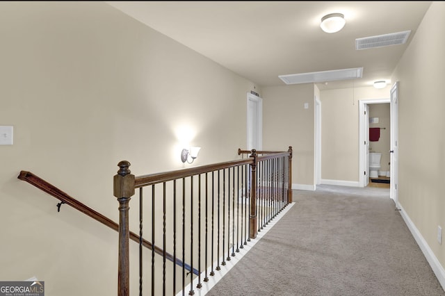 corridor with attic access, visible vents, an upstairs landing, and carpet