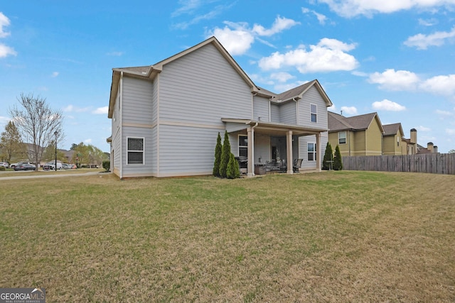 rear view of house with a lawn and fence