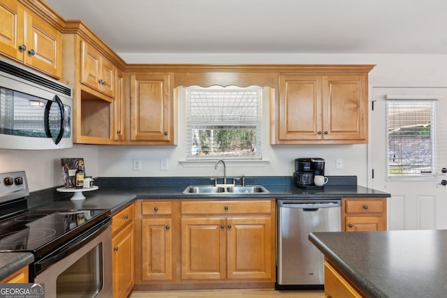kitchen featuring a sink, dark countertops, appliances with stainless steel finishes, and brown cabinets