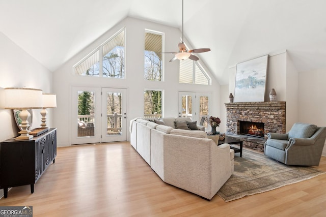 living room featuring a fireplace, lofted ceiling, ceiling fan, and light wood-style floors
