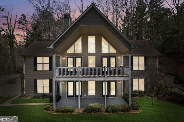 back of property with a chimney, a patio, and a yard