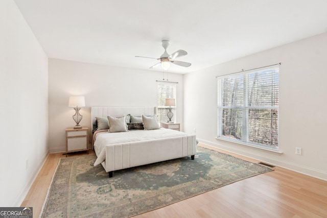 bedroom featuring baseboards, visible vents, ceiling fan, and wood finished floors