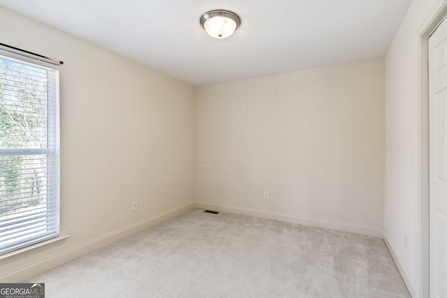 empty room featuring baseboards, a wealth of natural light, and light colored carpet