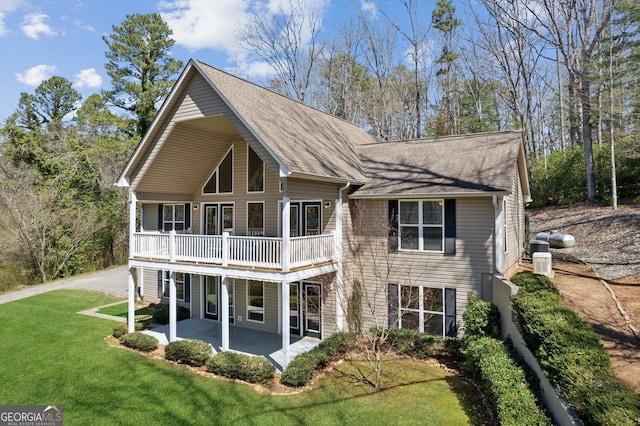 rear view of house with a lawn, roof with shingles, and a patio area